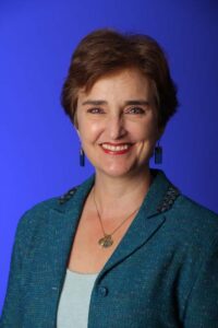 A woman in a blue jacket smiling for the camera.